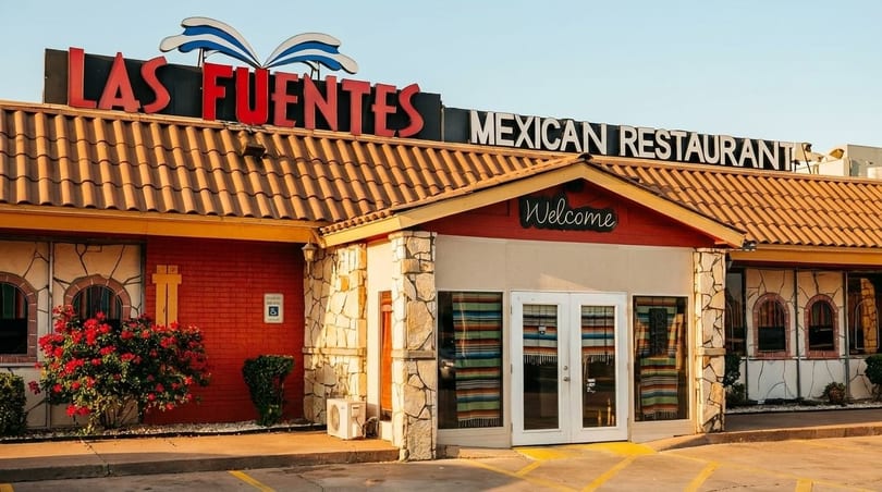 Exterior of Las Fuentes Mexican Restaurant with red brick, stone accents, and a "Welcome" sign.