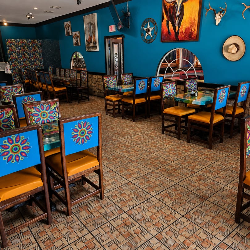 Vibrant restaurant interior with blue walls, colorful chairs, and Southwestern decor.